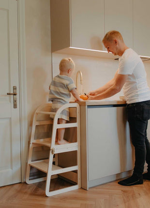 Vader helpt kind op witte Leg&Go transformeerbare keukentoren 2-in-1 bij aanrecht in keuken.