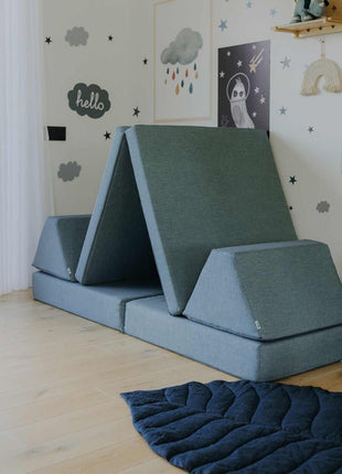 Turquoise Monboxy Montessori speelbank in tentopstelling met trapvormige kussens – uitdaagt tot motorisch spel en ruimtelijk inzicht.