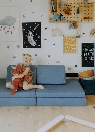 Kind zit op turquoise Monboxy Montessori speelbank met knuffel – speels en comfortabel moment in een veilige speelomgeving.