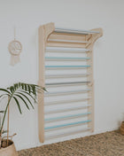 Zweeds klimwand systeem pastel gemonteerd aan witte muur met gekleurde sporten zijaanzicht
