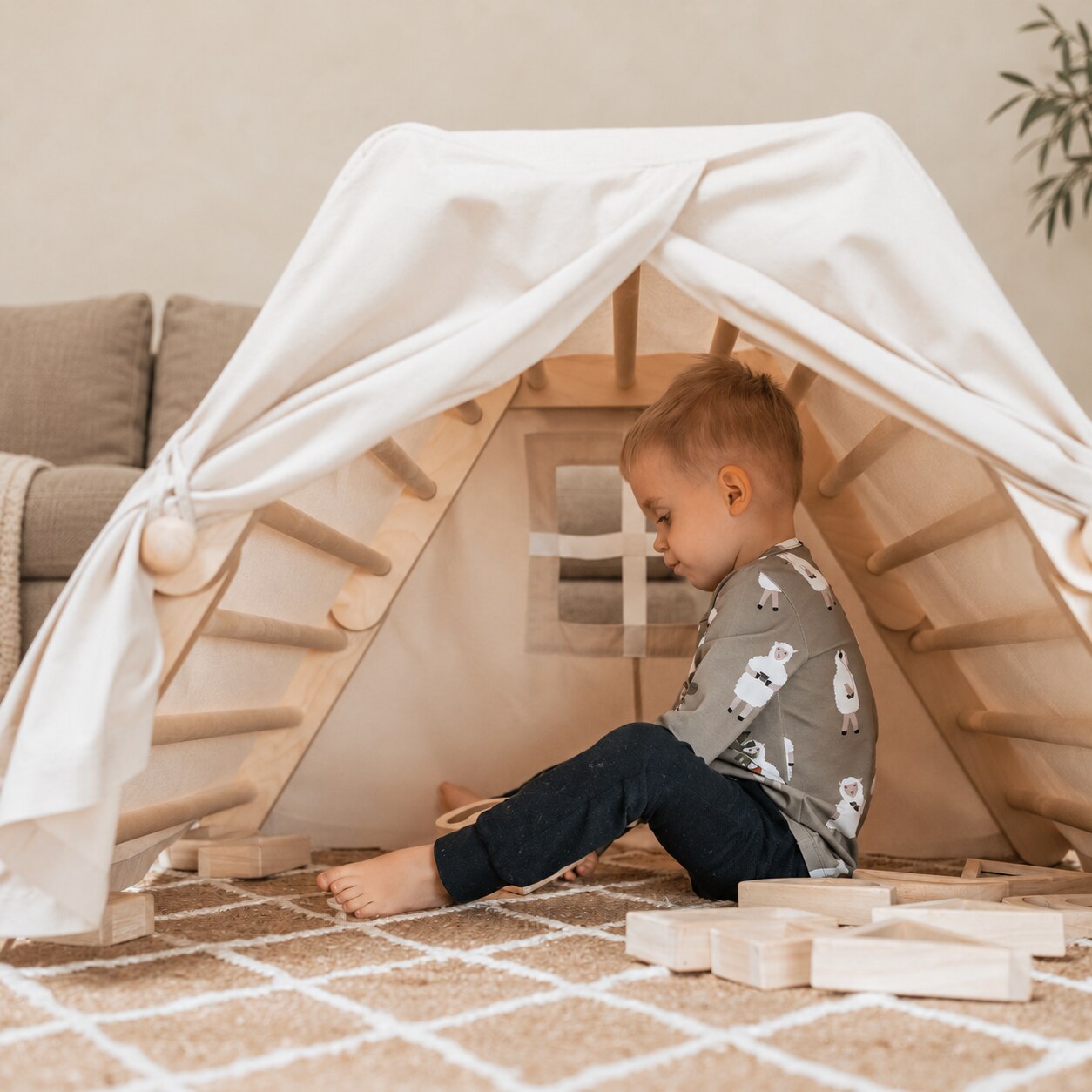 Een kind speelt met houten figuren in een katoenen speeltent.
